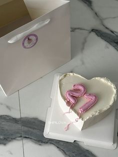 a heart shaped cake sitting on top of a white plate next to a box with the word love spelled in it