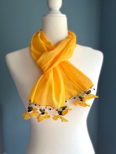 Elevate your summer and spring wardrobe with  exquisite cotton scarf for women.  This lightweight and airy accessory is a must-have for those who appreciate the beauty of delicate craftsmanship and unique design. Handcrafted with care, this yellow long scarf features edges adorned with charming crochet flowers, inspired by the traditional Turkish oya technique. Each flower is meticulously crafted, adding a touch of elegance and femininity to the summer scarf.  The intricate details and vibrant colors make this piece truly special and eye-catching. Made from high-quality cotton, this unique scarf is perfect for warmer seasons, providing a soft and breathable layer that keeps you cool and comfortable.  Whether you drape it over your shoulders, tie it as a headscarf, or wrap it around your ne Luxury Yellow Scarf For Summer, Elegant Orange Summer Scarf, Yellow Bohemian Shawl Silk Scarf, Casual Yellow Scarf, One Size, Yellow One-size Shawl Scarves, Flower Scarf, Scarf Gift, Summer Scarves, Floral Scarf