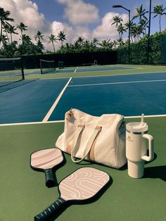 a tennis court with a bag, racket and cup on it