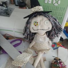 a creepy doll sitting on top of a table next to scissors and other crafting supplies