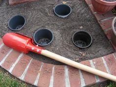 a red baseball bat laying on top of a pile of dirt next to buckets