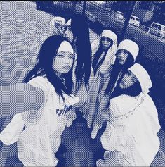 four women standing next to each other in front of a body of water wearing head coverings