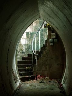 a dark tunnel with stairs leading up to the top and bottom, in front of an open door