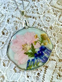 a glass pendant with flowers in it on a lace tablecloth