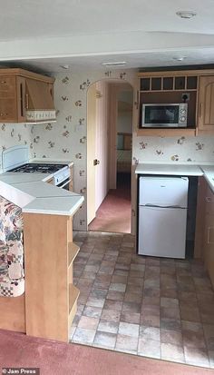 an empty kitchen with tile flooring and wooden cabinetry in the middle, next to a white stove top oven