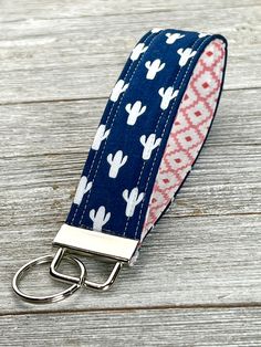 a keychain with a blue and white cactus print on it sitting on a wooden surface