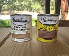 two cans of wood stain sitting on top of a wooden table next to each other