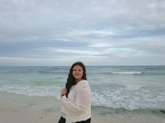 a woman standing on top of a beach next to the ocean