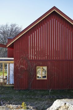 a red house with white doors and windows on the outside, in front of some trees