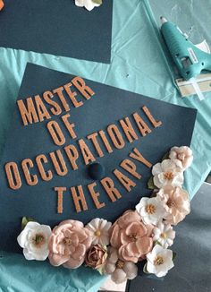 a graduation cap that says master of occupnational therapy on it with flowers around it