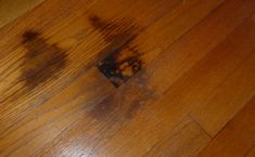 the wood floor is brown and has stains on it