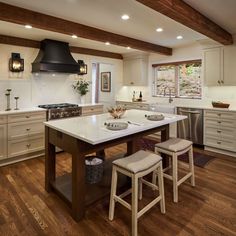 a large kitchen with an island in the middle and two stools at the end