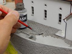 a person is painting a house with acrylic paint and a red brush in front of it