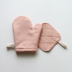 two pink oven mitts sitting next to each other on top of a white surface