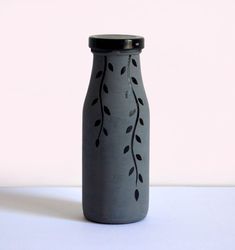 a gray vase with black leaves on it