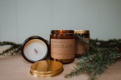 a candle sitting on top of a wooden table next to a pine branch and a gold plate