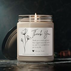 a candle with a thank you label sitting on top of a table next to other items