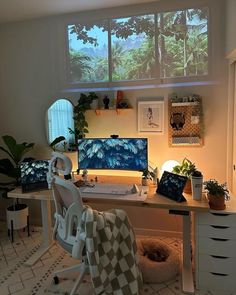 a desk with a computer on top of it in a room filled with plants and other items