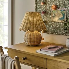 a wicker lamp sitting on top of a wooden table next to a potted plant