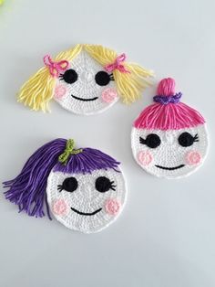 three handmade felt faces with different colored hair on white surface, including one girl and one boy