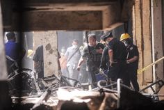 several men are standing in front of a building that has been demolished and is surrounded by rubble