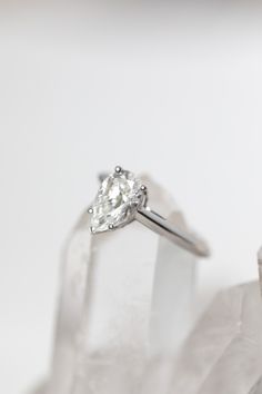 a white diamond ring sitting on top of a piece of clear glass with the reflection of it