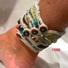 a person's foot wearing a bracelet with beads and buttons on the bottom of it