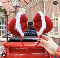 a hand holding up a red bow hat