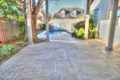 an empty patio with a pool in the back ground and trees on either side of it