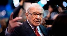 an older man wearing glasses and a red tie talking to the camera while surrounded by people