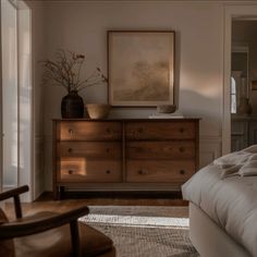 a bed sitting next to a wooden dresser in a bedroom