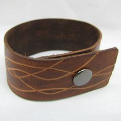 "The Round Up leather Cuff is made of tooled thick leather. It has been hand tooled, carved, and dyed. It has an adjustable metal snaps fastener. A waterproofing leather conditioner has been applied to the Cuff to beautify, condition, and strengthen the leather so it will hold up for a lifetime of use. Measurements: Total Length- 10\" (25.5cm) With-1 1/4\" (3cm) 1st snap is set at 7 1/4\" (18.5cm) 2nd snap is set at 8\" (20.5cm) If you like the design and need it bigger or smaller, I am happy to Leather Concho Cuff Bracelet, Leather Cuff Bracelet With Concho, Adjustable Hand Tooled Leather Cuff Bracelet, Brown Leather Concho Bracelet, Adjustable Leather Cuff Bracelet Hand-stitched, Engraved Brown Leather Bracelet, Leather Cuff Bracelet With Rivets, Brown Engraved Leather Bracelet, Brown Leather Cuff Jewelry