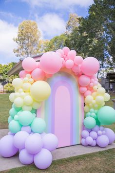 an arch made out of balloons in the shape of a rainbow is on display outside