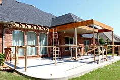 a house being built with wood and brick sidings on the front porch, attached to a covered patio area