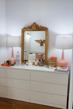 a white dresser topped with a mirror and two lamps