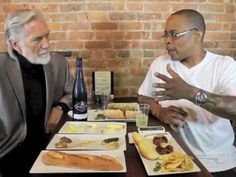 two men sitting at a table with plates of food