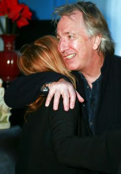 a man and woman hugging each other in front of a table with flowers on it