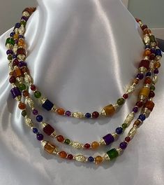 This vintage necklace from an Estate sale is a stunning piece that will add a touch of retro beauty to any outfit. With its layered and beaded design, it features a variety of colorful beads and a gold-colored embellishments and a Spring Ring closure. The necklace measures 22 inches in length and is perfect for a range of occasions, including Mother's Day, Christmas, graduation, anniversary, birthday, confirmation/communion, and Valentine's Day. This necklace is a great choice for anyone who lov Vintage Multi-strand Beaded Necklaces With Colorful Beads, Vintage Multi-strand Beaded Necklace With Colorful Beads, Vintage Multi-strand Colorful Beaded Necklaces, Elegant Double Strand Colorful Beaded Necklaces, Elegant Double Strand Beaded Necklace, Multicolor Beads For Costume Jewelry Party, Multicolor Beads For Party Costume Jewelry, Vintage Colorful Beaded Necklaces For Festive Occasions, Vintage Multicolor Multi-strand Beads