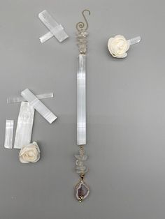 an assortment of jewelry on a table with white flowers and ribbons hanging from it's sides