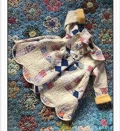 a baby's quilted outfit laying on top of a blue floral rug with yellow socks