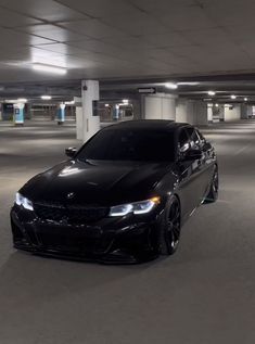 a black car is parked in an empty parking garage with no one around or looking at it