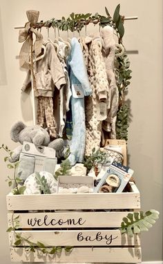 a welcome baby sign with teddy bears and other items in it on a wooden crate