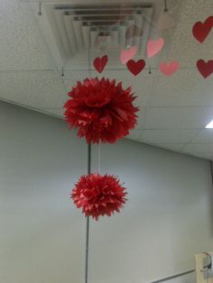 red paper flowers hanging from the ceiling in an office cubicle with hearts on it