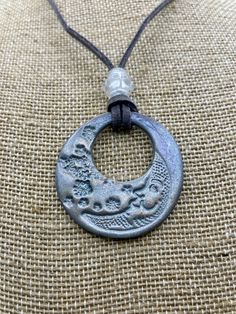 This is a 1 1/2 inch x 1 1/2 inch lightweight Pendant made with Slate Premo polymer clay. Stamped by hand using mica powder to shine. It has 24 inch Leather cord, lobster claw clasp, and plastic decorative bead. Adjustable Hand Cast Round Pendant Necklaces, Clay Moon, Necklace Clay, Crescent Moon Pendant, Decorative Beads, Moon Pendant Necklace, Crescent Moon Necklace, Mica Powder, Gothic Jewelry