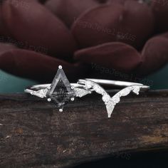 two white gold and silver rings with diamonds in the shape of birds sitting on a piece of wood