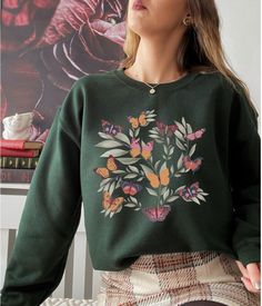 Our botanical butterfly shirt has a boho, cottagecore vibe. The vintage inspired design would make the perfect gift for any teenage girl or college student gift. Size up for an oversized look! ABOUT THE PRODUCT: Unisex Heavy Blend™ Crewneck Sweatshirt | GILDAN 18000 (Customer Favorite) A sturdy and warm sweatshirt bound to keep you warm in the colder months. A pre-shrunk, classic fit sweater that's made with air-jet spun yarn for a soft feel and reduced pilling. * 50% cotton, 50% polyester * Pre-shrunk * Classic fit with no center crease * 1x1 athletic rib knit collar with spandex * Air-jet spun yarn with a soft feel and reduced pilling * Double-needle stitched collar, shoulders, armholes, cuffs, and hem The size chart is listed in photos above. Please use the measurement for the most accu Demicore Aesthetic, Fairycore Crew Neck Top For Fall, Green Fairycore Tops For Spring, Green Fairy Grunge Tops For Spring, Cotton Crew Neck T-shirt In Fairycore Style, Summer Fairycore Crew Neck T-shirt, Cottagecore Crew Neck Top With Graphic Print, Cotton Fairycore T-shirt With Crew Neck, Spring Fairycore Crew Neck T-shirt