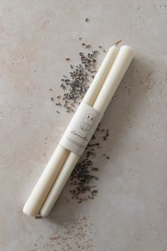 two candles sitting on top of a table next to some dried lavender and anise