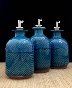 three blue vases sitting on top of a wooden table