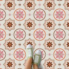 someone's feet standing in front of a flower patterned wallpaper with pink and brown flowers