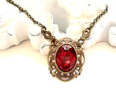 Beautiful victorian style pendant necklace made of a lovely oxidized brass filigree cabochon base, American made, and a vintage ruby red rhinestone cabochon. The size of the cabochon is 13 x 18 mm. The necklength is approximately 49 cm. (19.3 inches) For more jewelry please visit our shop: http://www.minouc.etsy.com For combined shipping please contact us. We also combine shipping with our other Etsy shop where we sell vintage fabrics and finds from Holland and France: http://www.minoucbrocante. Elegant Red Locket Necklaces, Victorian Antique Gold Necklaces For Valentine's Day, Victorian Antique Gold Necklace For Valentine's Day, Antique Brass Necklaces For Valentine's Day, Victorian Ruby Pendant Jewelry, Red Ruby Victorian Necklace, Victorian Brass Necklace For Valentine's Day, Red Filigree Vintage Jewelry, Vintage Ruby Filigree Jewelry